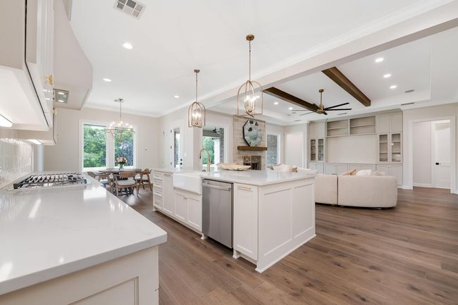 Kitchen featuring a ceiling fan, a stone fireplace, dark wood-style flooring, white cabinets, and open floor plan | Image 22