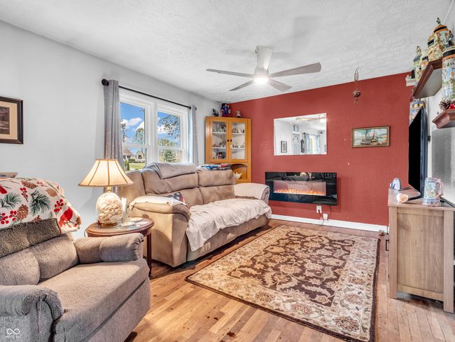 living room with hardwood / wood-style flooring, ceiling fan, a textured ceiling, and a glass covered fireplace | Image 12