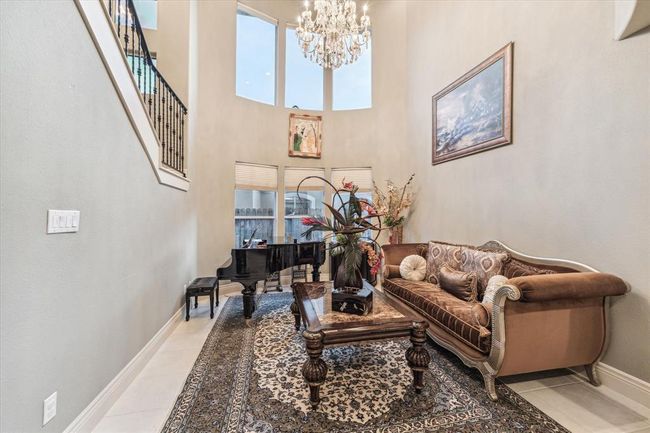 Across from the Dining Room is the Formal Living Room, another two-story entertaining space with columns, soaring ceilings, floor-to-ceiling windows & a Tiffany's Chandelier that stays. | Image 23