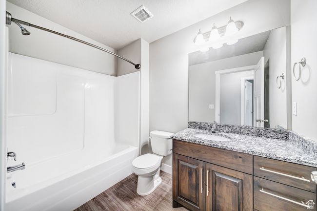Bathroom with shower / washtub combination, visible vents, toilet, vanity, and wood finished floors | Image 16