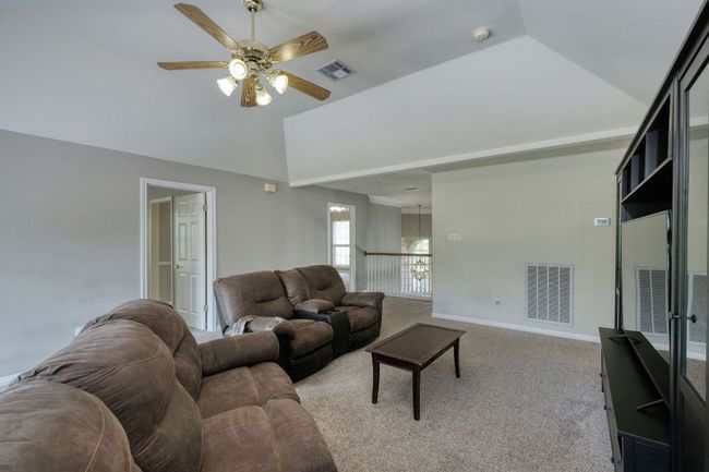 Living area featuring a ceiling fan, visible vents, high vaulted ceiling, and light colored carpet | Image 20