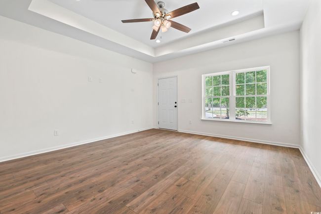 Spare room featuring a raised ceiling, dark wood-style floors, a ceiling fan, baseboards, and recessed lighting | Image 4
