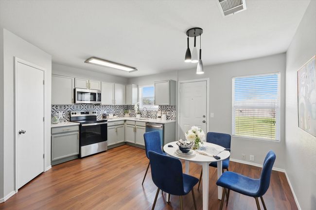 Kitchen with stainless steel appliances, gray cabinetry, decorative backsplash, wood finished floors, and light countertops | Image 11