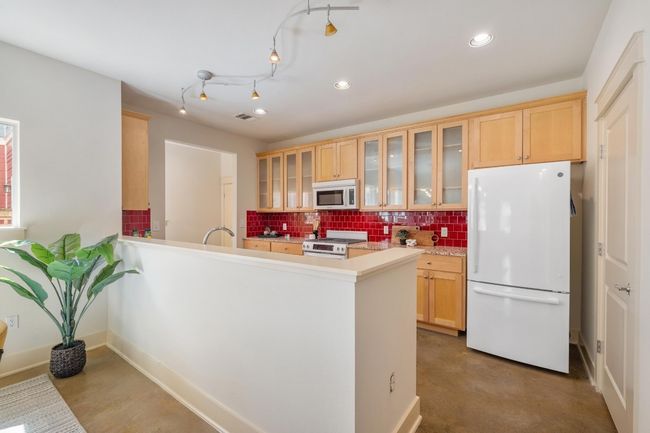Matching custom tile backsplash and recycled glass countertops, complimented by wood cabinetry, create a space that’s equal parts eye-catching and efficient | Image 12