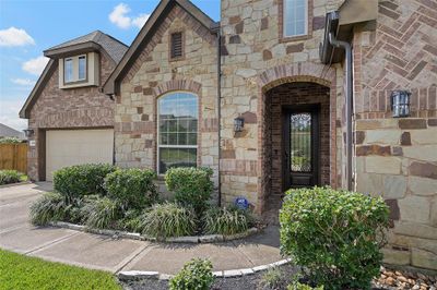 A charming walkway lined with blooming foliage leads up to the covered front entry of the home! This home also boasts a 3-car tandem garage! | Image 3