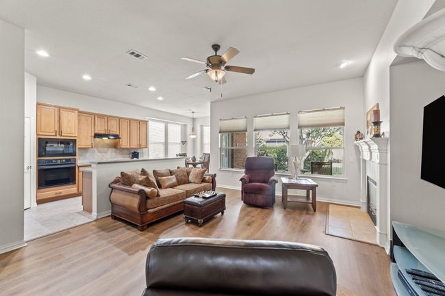 Living room featuring a ceiling fan, light wood-style floors, recessed lighting, a fireplace, and baseboards | Image 15