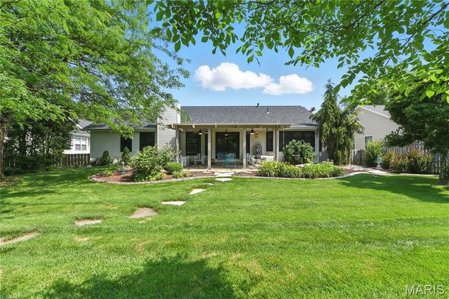Rear view of house with ceiling fan, a patio area, a chimney, and roof with shingles | Image 16