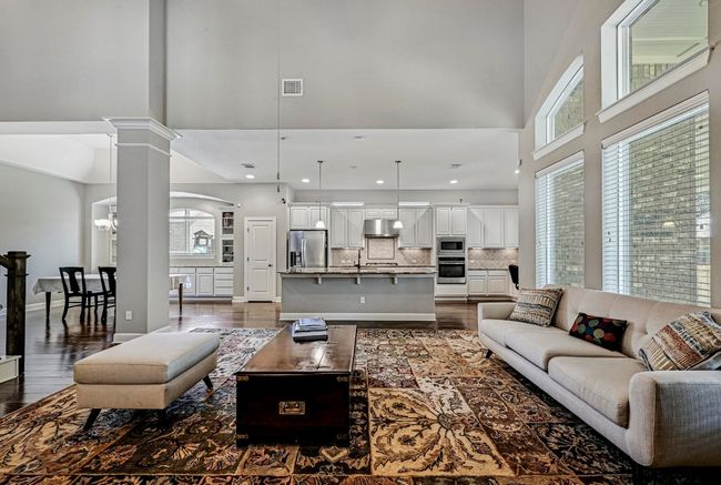 Living room featuring a high ceiling, dark wood finished floors, healthy amount of natural light, decorative columns, and recessed lighting | Image 6