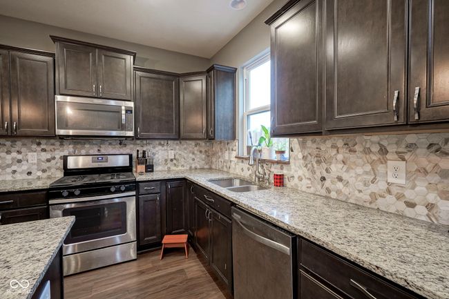 kitchen with appliances with stainless steel finishes, a sink, dark brown cabinets, and dark wood-type flooring | Image 11