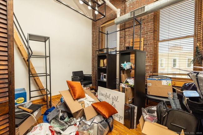 Bedroom with a loft for extra space, exposed brick walls, high ceilings, and large windows that allow in tons of natural light | Image 12