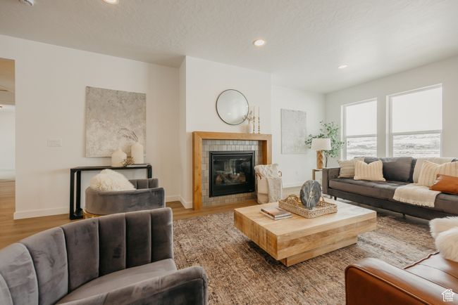 Living area with wood finished floors, a tiled fireplace, recessed lighting, and baseboards | Image 10