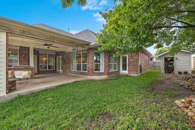 Rear view of property featuring a ceiling fan, brick siding, a patio area, and roof with shingles | Image 30