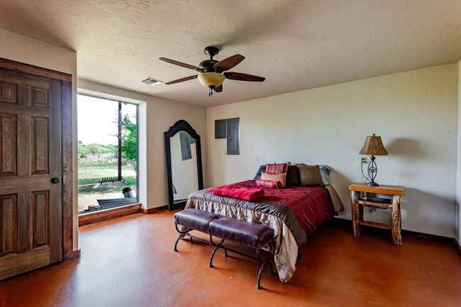 Bedroom featuring visible vents, access to exterior, a ceiling fan, baseboards, and finished concrete floors | Image 27