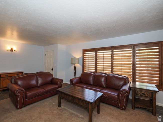 Living area with a textured ceiling, carpet, and baseboards | Image 5