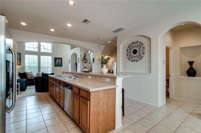 Kitchen with sink, a breakfast bar, appliances with stainless steel finishes, a center island with sink, and light tile patterned flooring | Image 5