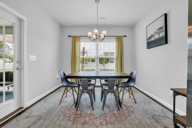 Dining space with wood finished floors, visible vents, baseboards, and an inviting chandelier | Image 24
