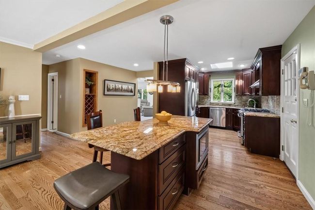 Kitchen with light hardwood / wood-style flooring, stainless steel appliances, hanging light fixtures, tasteful backsplash, and a center island | Image 5