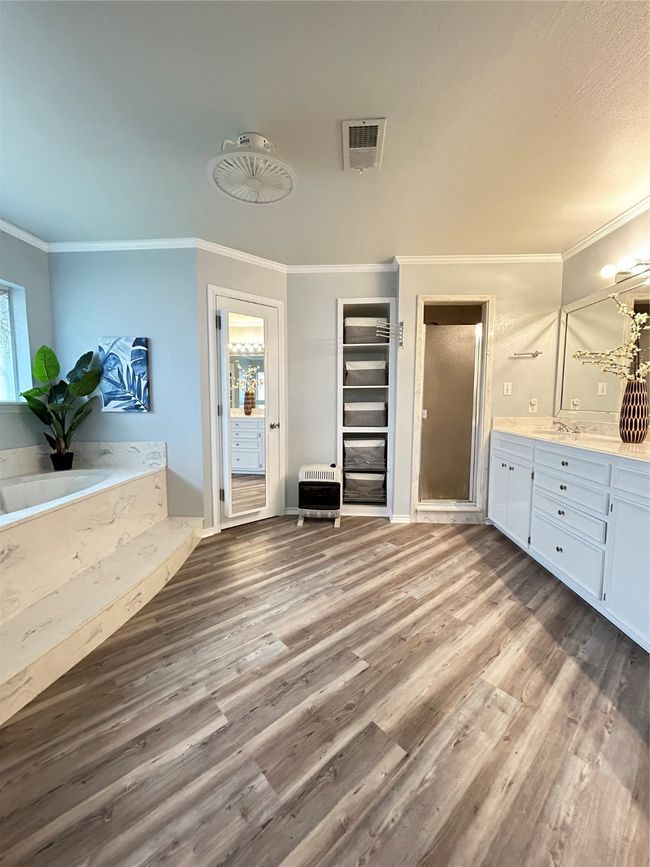 Bathroom with heating unit, visible vents, a stall shower, and wood finished floors | Image 4