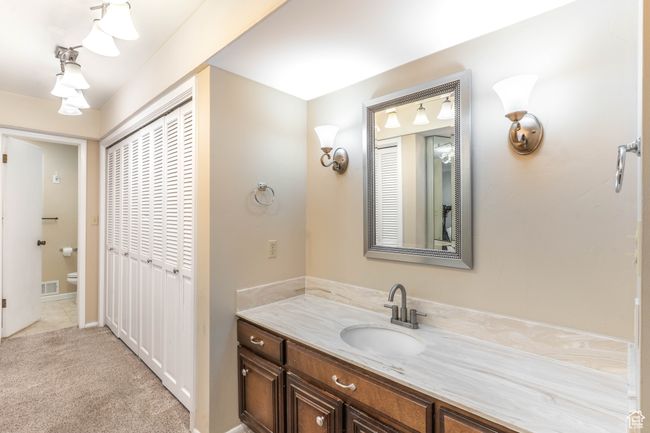 Bathroom featuring toilet, vanity, visible vents, and a closet | Image 17