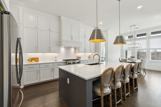 Kitchen featuring stainless steel appliances, a sink, dark wood-style flooring, decorative backsplash, and light countertops | Image 10