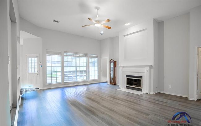 Bright and spacious living room with high ceilings, large windows, and a fireplace. Features modern flooring and a ceiling fan. Ideal for family gatherings. | Image 17