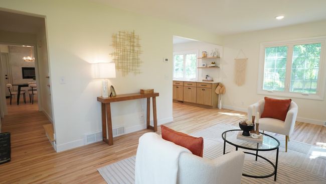 The copious amounts of windows in the living room allow for a ton of natural light. It offers direct access to both the kitchen and dining space, as well as the upper level stairway off the front entry. | Image 6