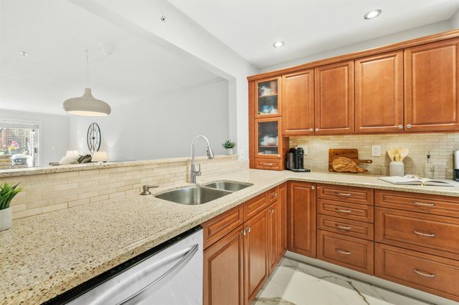Kitchen featuring dishwasher, marble finish floor, light stone counters, and a sink | Image 7