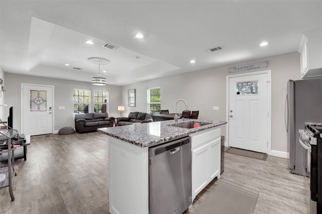 Kitchen with light wood-style floors, a tray ceiling, visible vents, appliances with stainless steel finishes, and a sink | Image 18