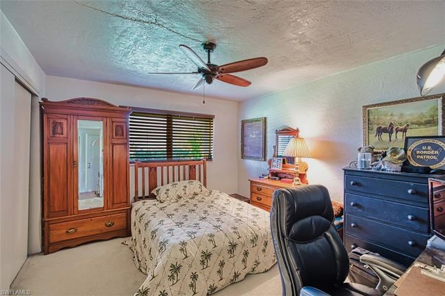 Bedroom with light carpet, a textured ceiling, ceiling fan, and a desk | Image 28