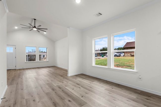 Unfurnished living room featuring ornamental molding, ceiling fan, light wood-type flooring, and high vaulted ceiling | Image 7