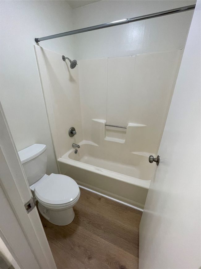 Bathroom featuring toilet, hardwood / wood-style flooring, and shower / washtub combination | Image 12