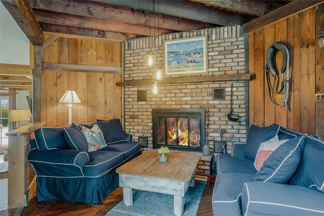 Living room featuring wood walls, wood finished floors, beam ceiling, and a fireplace | Image 6