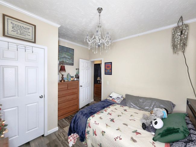 Bedroom with a textured ceiling, hardwood / wood-style floors, a notable chandelier, and ornamental molding | Image 22