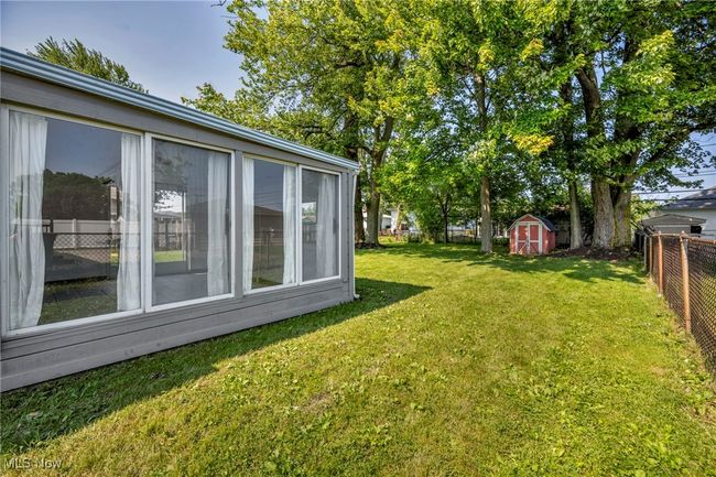 Fenced backyard featuring a storage unit | Image 41