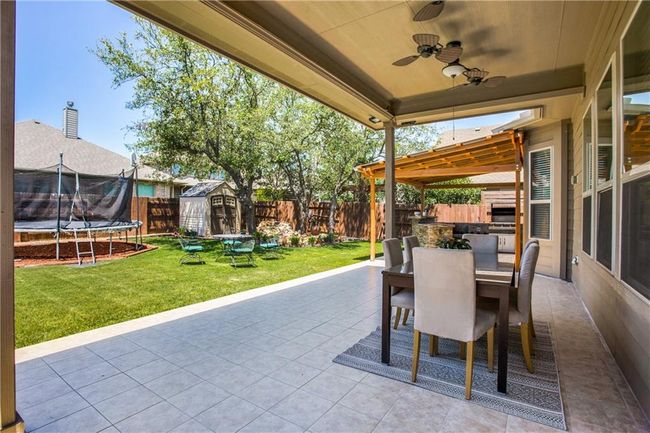 Fenced backyard with outdoor dining area, a storage shed, a trampoline, and a patio | Image 23