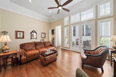 Sophisticated interior with tall ceilings, crown molding, hardwood floors and large shuttered windows that flood the space with natural light, opening to a private outdoor patio. | Image 3