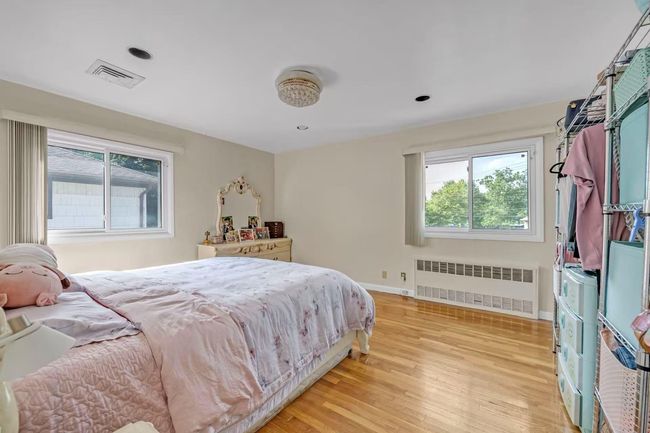 Bedroom with multiple windows, light wood-style floors, and radiator heating unit | Image 8