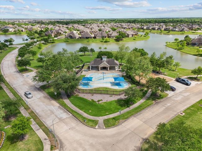 This photo showcases a picturesque neighborhood featuring a community pool, surrounded by lush greenery and walking paths. The area includes scenic water views with houses lining the tranquil lakes, offering a serene, family-friendly environment. | Image 42