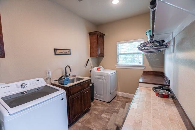 Laundry room with cabinet space, independent washer and dryer, baseboards, and light stone finish flooring | Image 28
