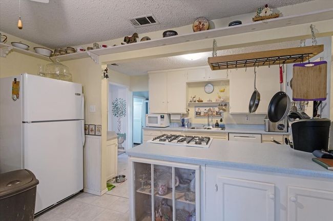 Kitchen featuring white appliances, sink, a textured ceiling, and white cabinets | Image 17