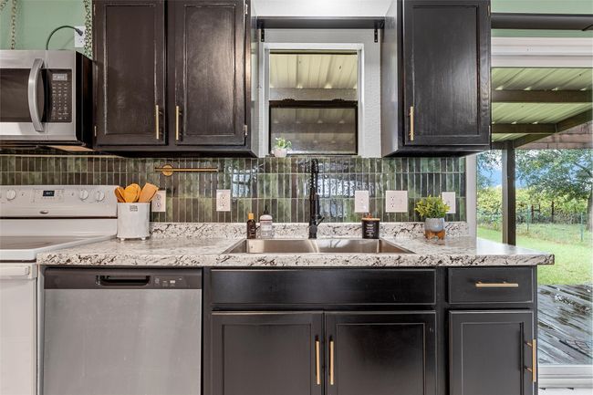Kitchen with stainless steel appliances, tasteful backsplash, and light stone countertops | Image 10