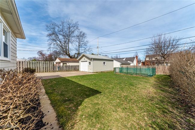 View of yard featuring concrete driveway, an outbuilding, a detached garage | Image 41