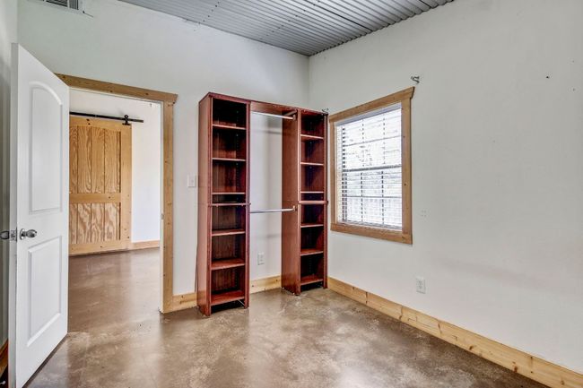 Unfurnished bedroom featuring a barn door, finished concrete flooring, baseboards, and visible vents | Image 29