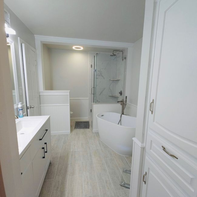 Bathroom featuring vanity, a freestanding bath, and a marble finish shower | Image 16