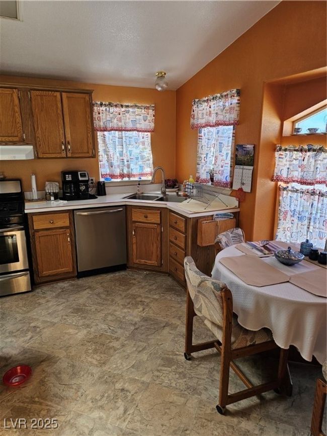 Kitchen featuring dishwashing machine, stove, brown cabinetry, and extractor fan | Image 25