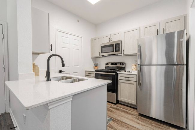 Kitchen featuring backsplash, sink, appliances with stainless steel finishes, light hardwood / wood-style floors, and kitchen peninsula | Image 6