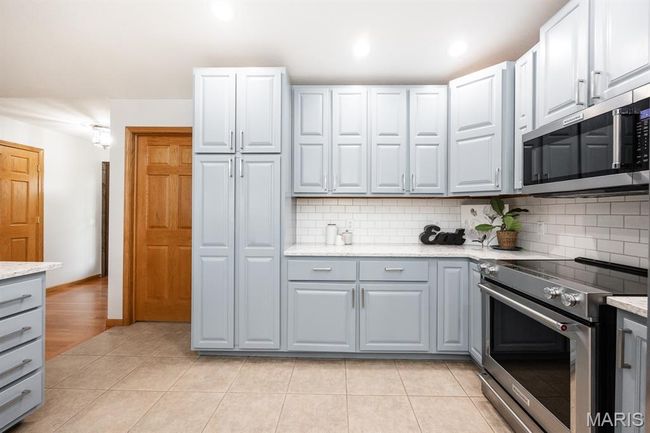 Kitchen with stainless steel appliances, decorative backsplash, gray cabinetry, light tile patterned floors, and recessed lighting | Image 19