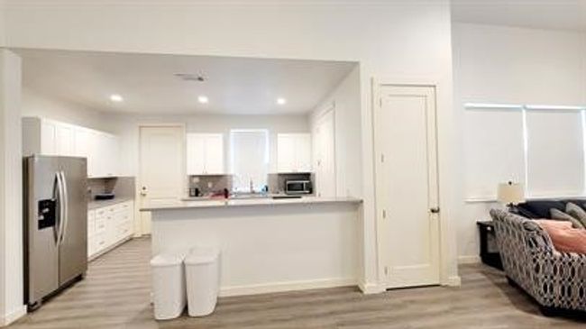Kitchen with stainless steel appliances, light wood finished floors, white cabinetry, a peninsula, and light countertops | Image 7