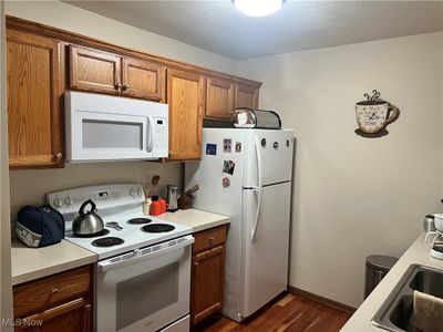 Kitchen with white appliances, dark wood-type flooring, and sink | Image 3