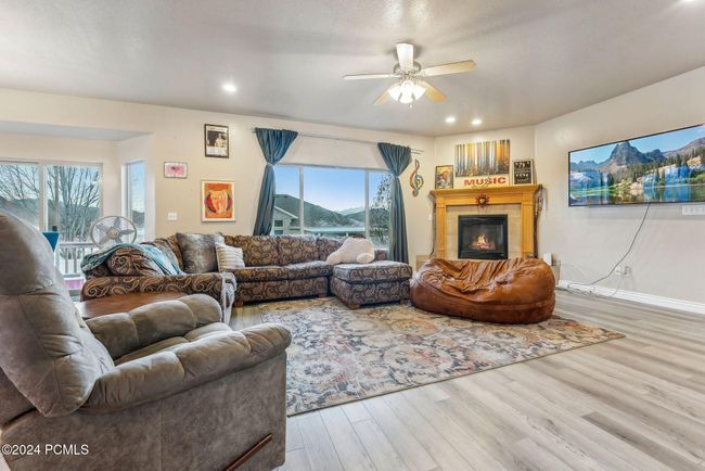 Living room with plenty of natural light, ceiling fan, wood-type flooring, and a tile fireplace | Image 6
